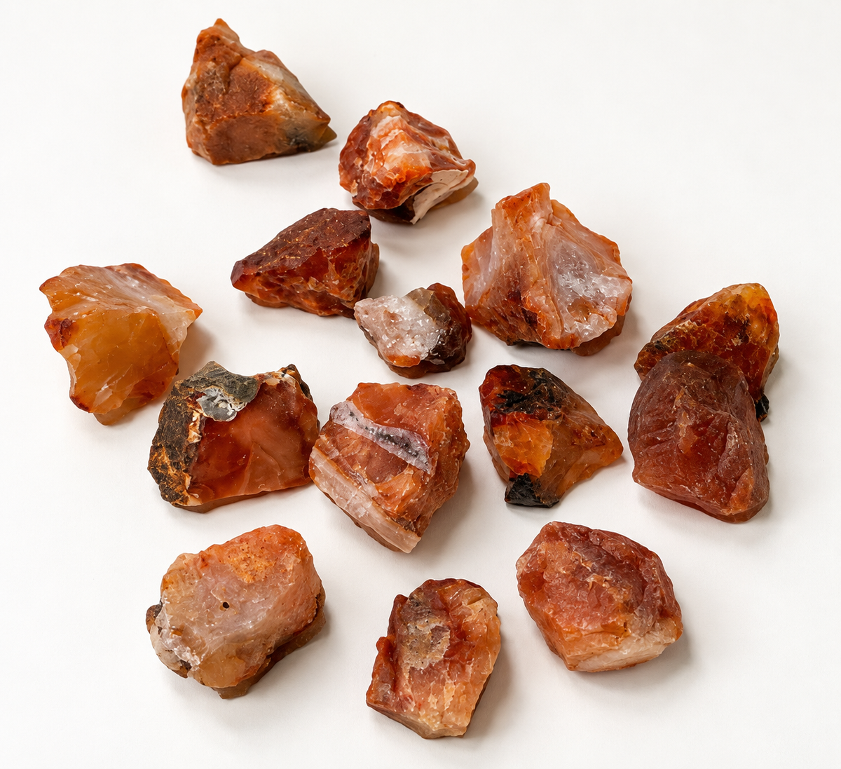 Assortment of natural rough Carnelian stones on a light surface showing warm orange amber and reddish brown colors