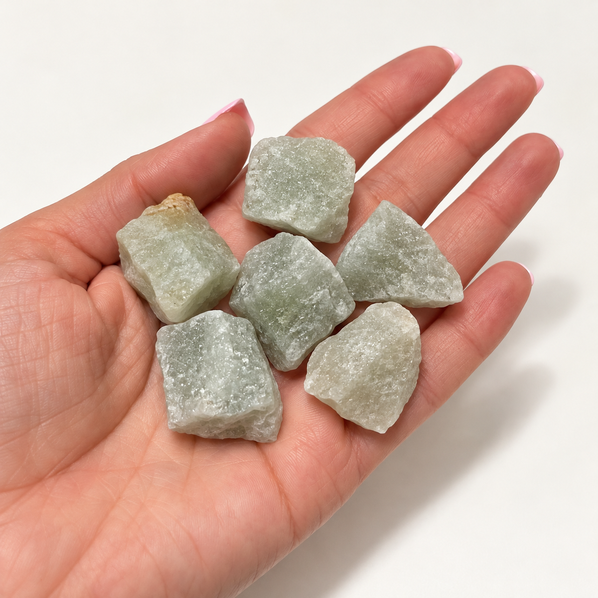Raw pale green aventurine stones held in an open hand for scale