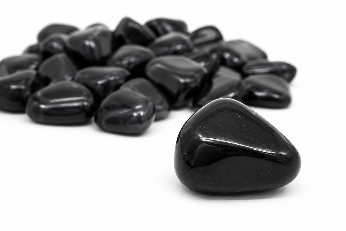 One tumbled Black Tourmaline stone with additional stones in the background