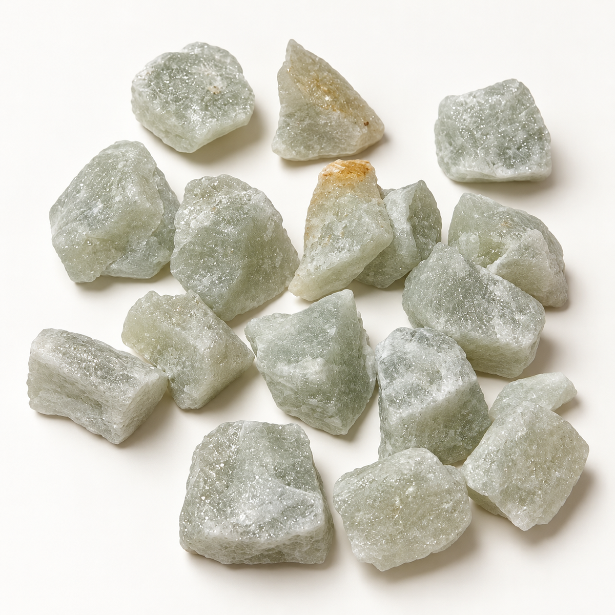 Assortment of pale green raw aventurine stones on a cream background, showing frosted surfaces and natural variation