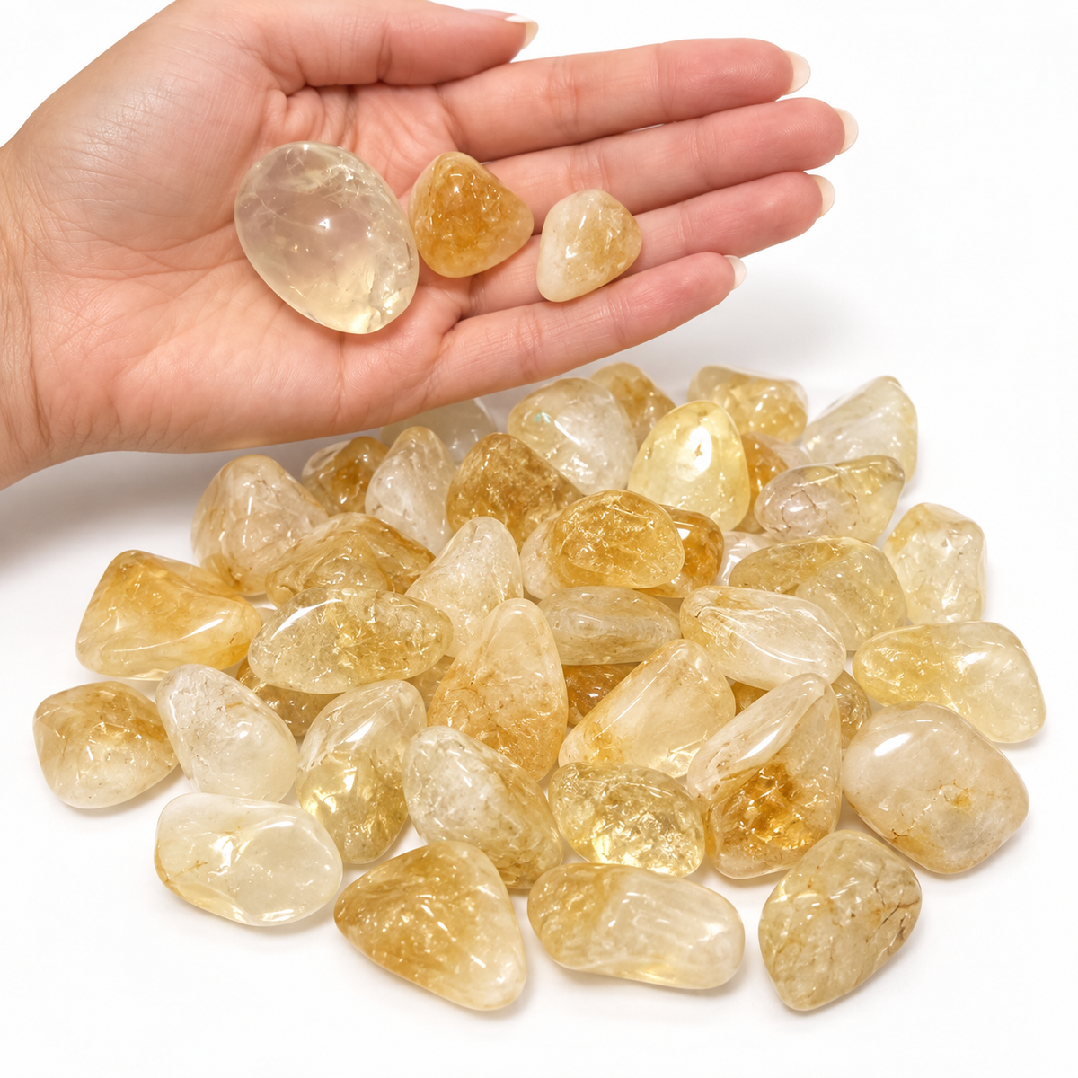 Citrine tumbled stones shown in hand for size reference