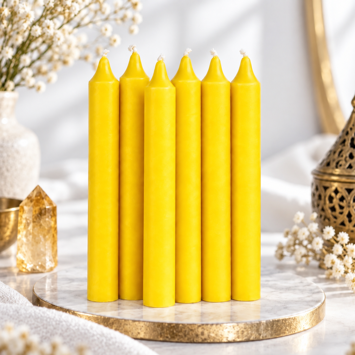 Set of six yellow 6-inch intention candles with white flowers and golden crystal on a bright white background